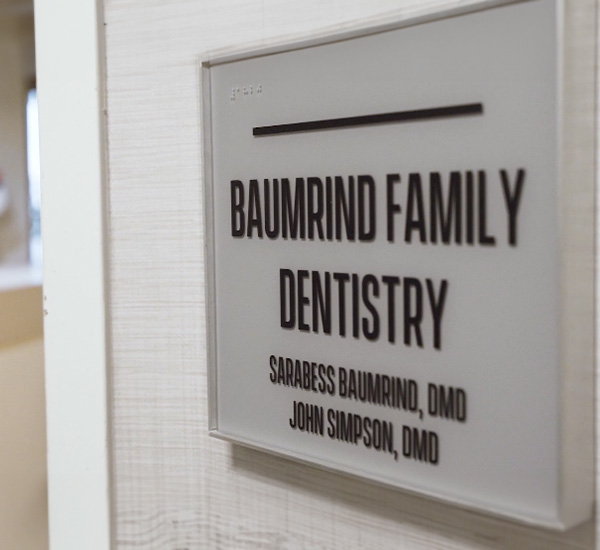 The image shows a sign for Baumind Family Dentistry with the names of dentists listed below.